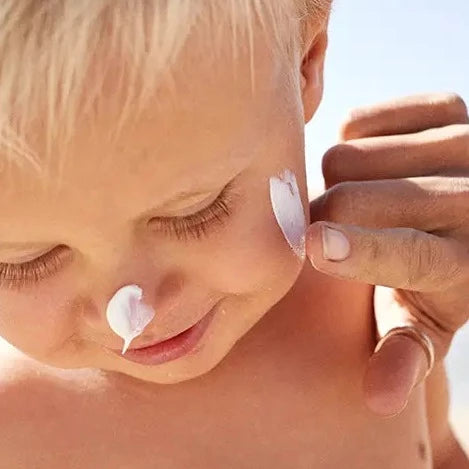 zinc oxide sunscreen being rubbed on to a little boys face
